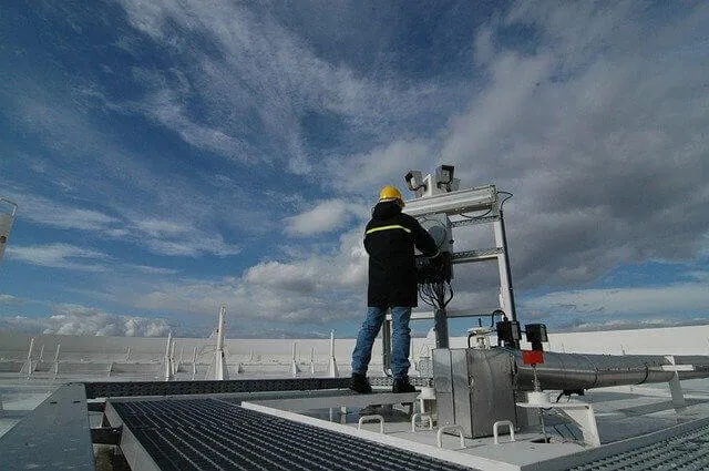 Picture of a man on a roof servicing an industrial air conditioner and HVAC system. 