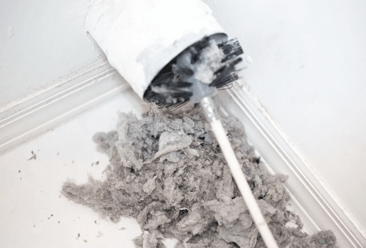 A picture of a brush cleaning lint out of a dryer vent.