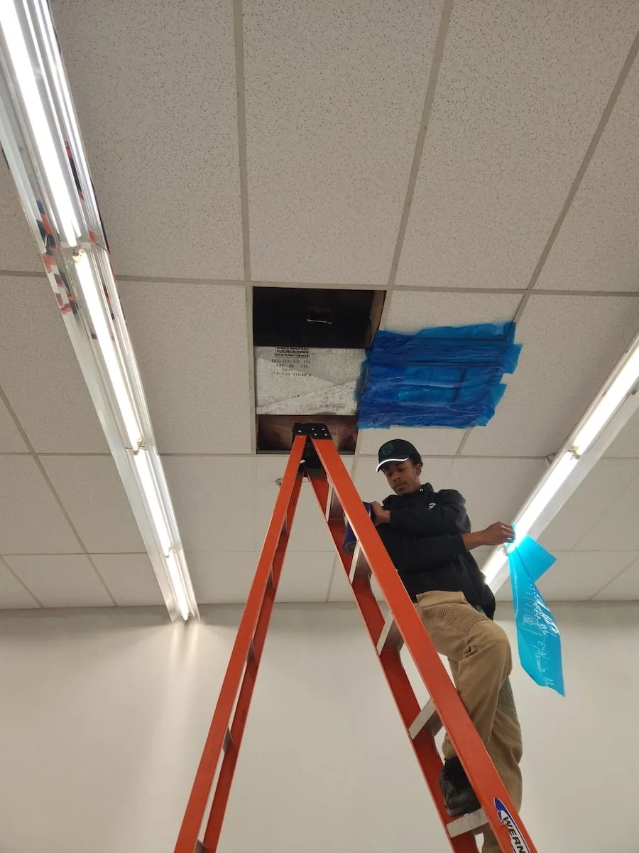 Planet Duct technician working on duct work on a ladder